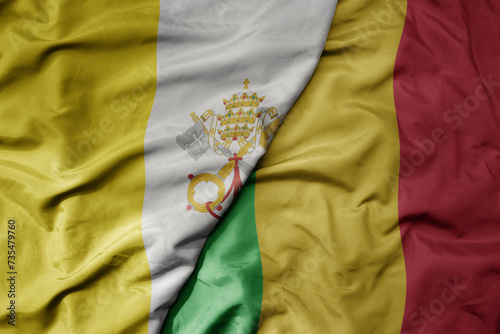 big waving national colorful flag of mali and national flag of vatican city.