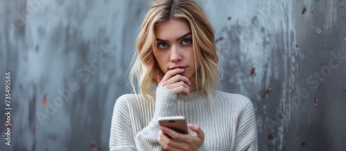 Attractive woman in stylish white sweater checking her smartphone for messages and updates