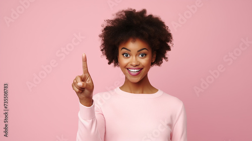 Excited African American Woman Pointing Upwards Against Pink Background. Copy space. Women’s Day.