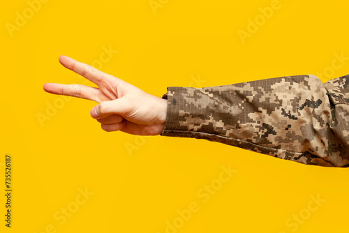Fotografie the hand of Ukrainian soldier in camouflage pixel uniform shows peace and number