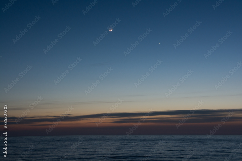 静かな海の夕暮れと三日月と金星
