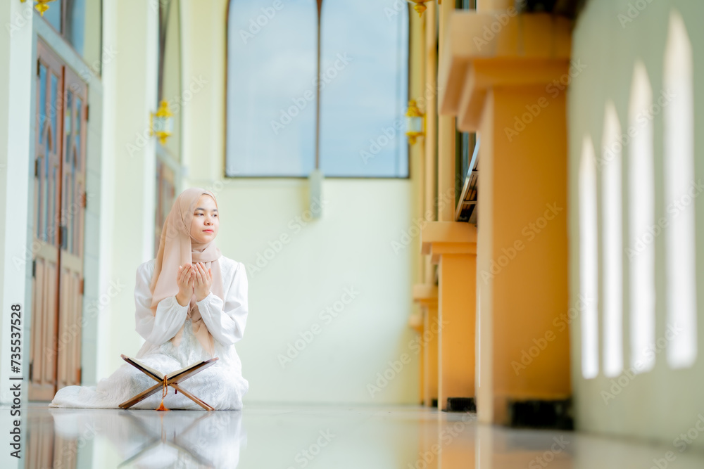 Ramadan, quran, The image of an Asian Muslim woman in the Islamic religion in hijab in cream color. reading the Quran and having a happy Staying in a beautiful mosque, Arabic word Holy Al Quran. Ramadan, quran, The image of an Asian Muslim woman in the Islamic religion in hijab in cream color. reading the Quran and having a happy Staying in a beautiful mosque, Arabic word Holy Al Quran.