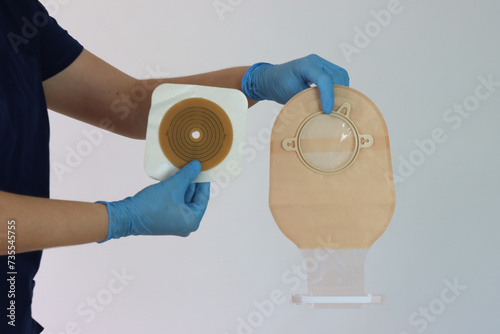 Health care professional holding the colostomy bag system with the hands wearing gloves  photo