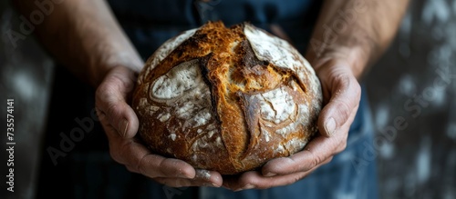Young person holding a freshly baked loaf of bread, close up shot for bakery concept and homemade healthy food