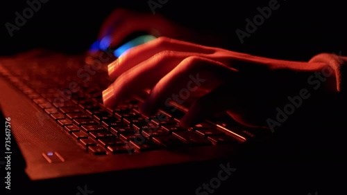 Hands of Gamer Playing Video Game at Computer in a Virtual Room at Night. Close up. Typing on the keyboard. Online eSports competition. Neon backlight, keyboard, computer mouse. Hacker or freelancer. photo
