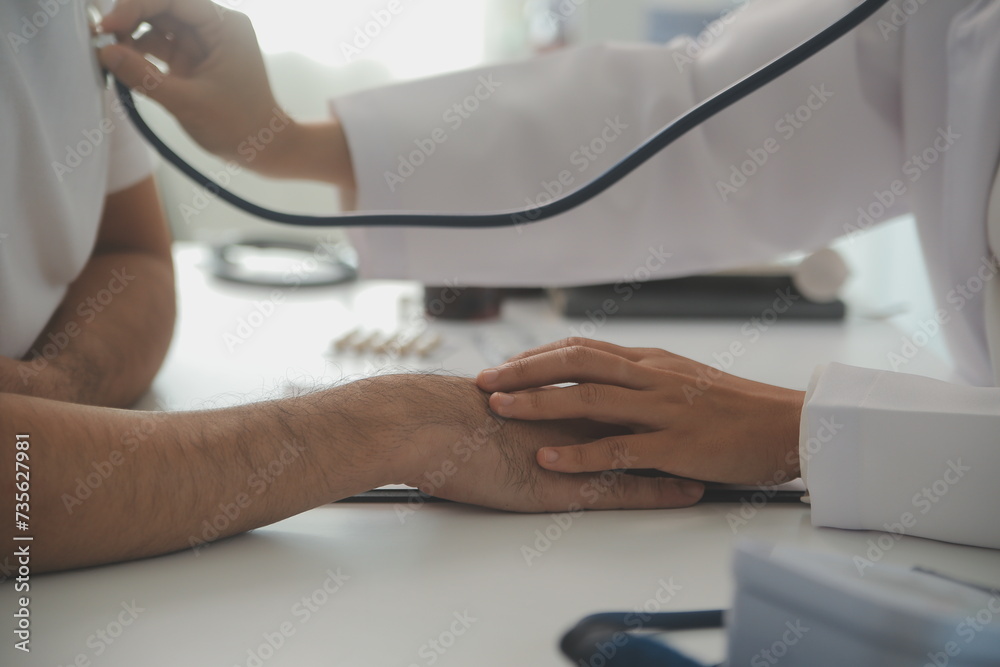 Fototapeta premium Young doctor is using a stethoscope listen to the heartbeat of the patient. Shot of a female doctor giving a male patient a check up