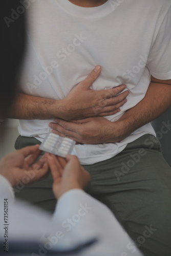 Man suffering with severe stomach pain sitting at home. Hand of mature guy holding abdomen suffering from ache, diarrhea or indigestive problem. Caucasian guy pressing on belly on painful sensation