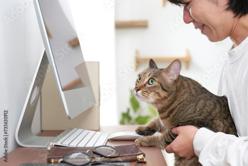 パソコンの前に座る女性と猫 photo
