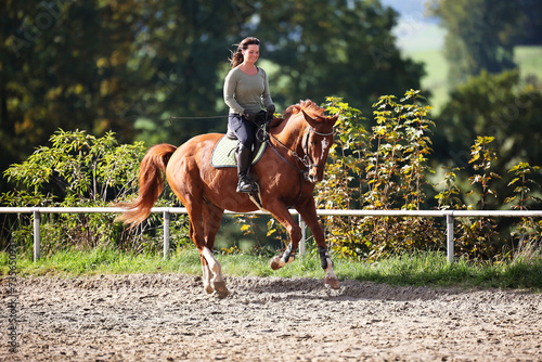 Horse woman rider riding in the sunshine at the riding arena. photo