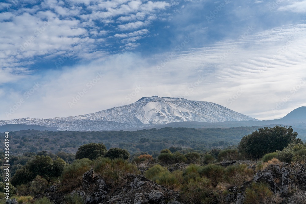 view of a snow-covered Mount Etna and the wild hills of the Sicilian backcountry