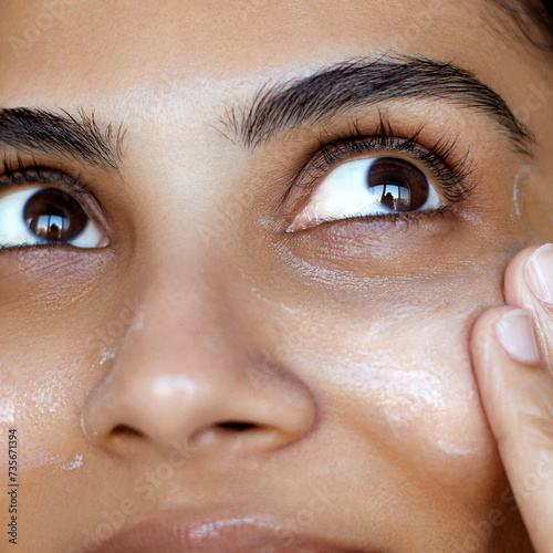 Close-up south asian woman portrait, one hand gently touching the face and applying a cream or skincare cosmetic mask, skin care and hydration. photo