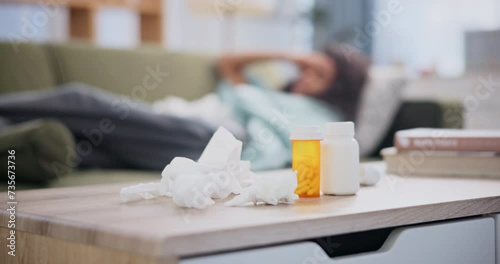 Pills, tissue and woman on sofa with headache for hay fever, allergy or stress at home. Female person, medicine and laying on couch with hand on head for pain, covid 19 or flu virus in living room photo