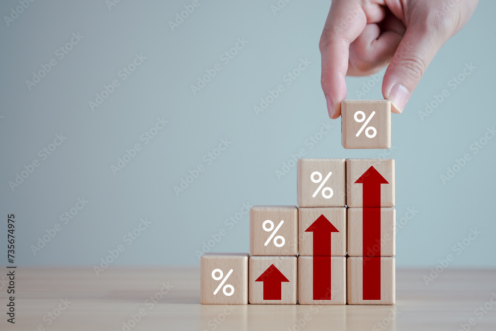 Interest rate finance and mortgage rates. Hand holding wooden block with percentage sign and rise of arrow up, financial growth, interest rate increase, inflation, sale price and tax rise concept. Interest rate finance and mortgage rates. Hand holding wooden block with percentage sign and rise of arrow up, financial growth, interest rate increase, inflation, sale price and tax rise concept.