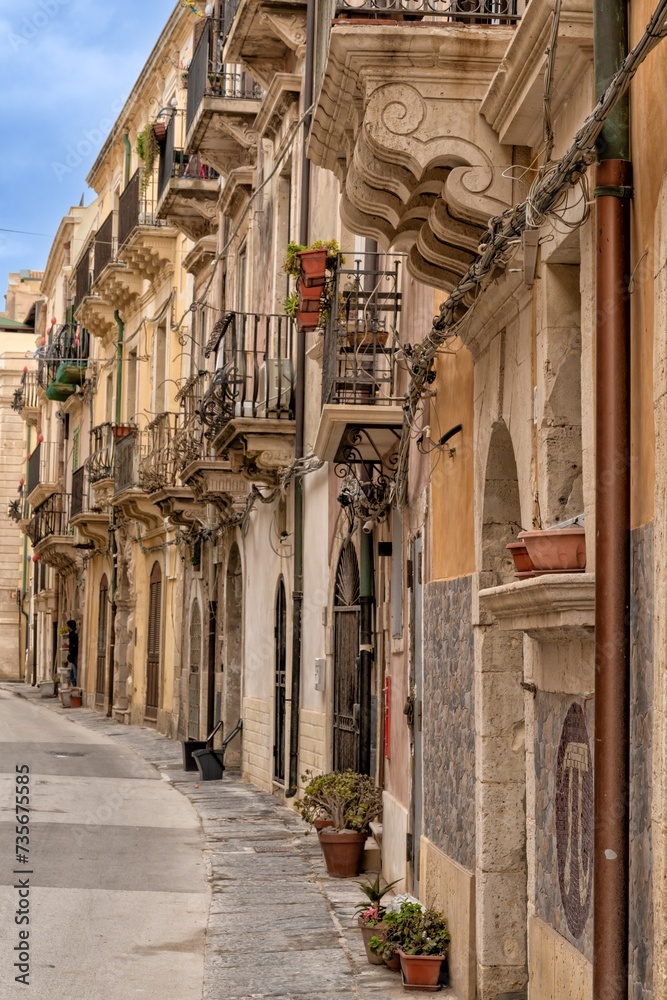 Old Town street with house fronts and balconies in the center of Isola di Ortigia