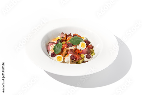 Roast beef salad with quail eggs and vegetables artistically arranged on a white plate