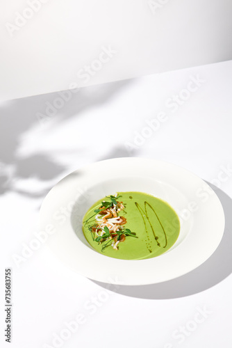 Spinach Cream Soup with Calamari Topping, Artfully Presented on a White Plate with Shadow, Perfect for Gourmet Food Advertising
