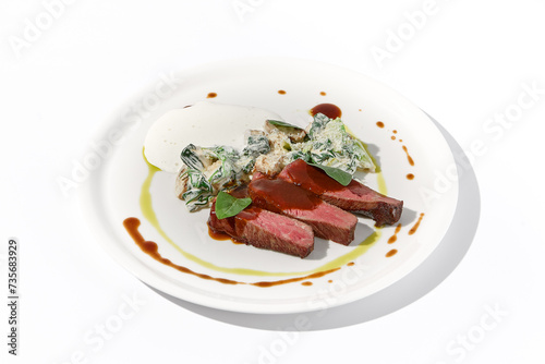 Beef steak with creamed spinach and mushrooms on elegant white dish, ideal for fine dining and gourmet cuisine