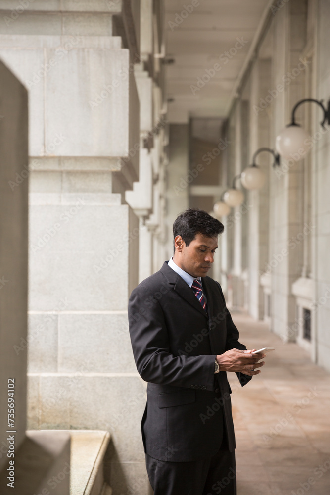 Indian businessman using his Smart phone outdoors. Indian businessman using his Smart phone outdoors.
