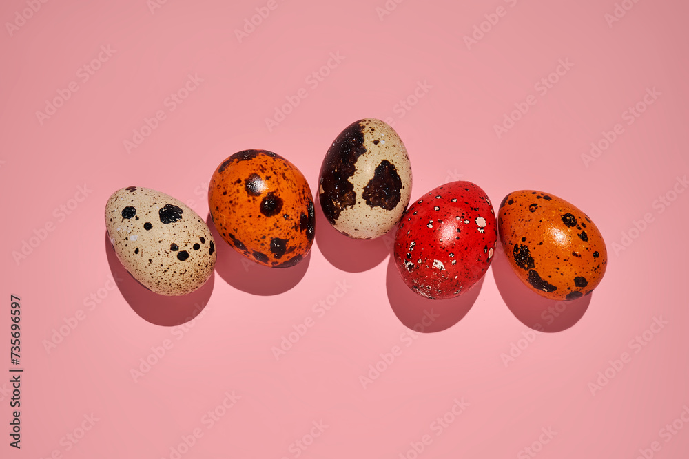 Easter composition of quail eggs and grass on a pink background.