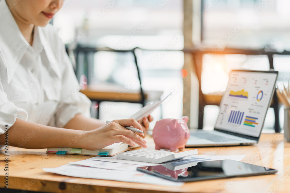 Focused financial professional using a calculator for budget analysis, with financial documents and a tablet on her desk. Focused financial professional using a calculator for budget analysis, with financial documents and a tablet on her desk.