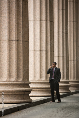 Indian Lawyer/businessman using a Smart Phone outside colonial building.