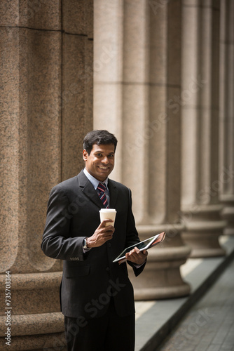 Indian Lawyer/businessman using tablet PC outside a colonial building.