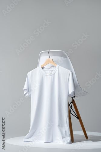 White blank t-shirt hanging on chair in empty room