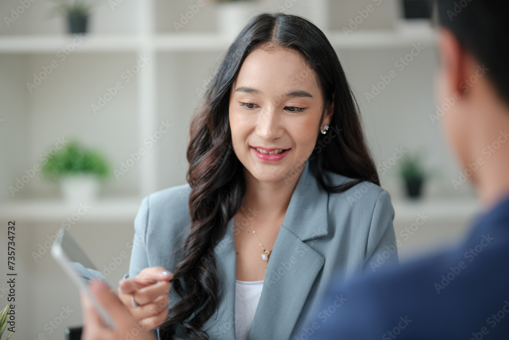 Obraz premium Two business workers smiling happy working sitting on desk at the office.