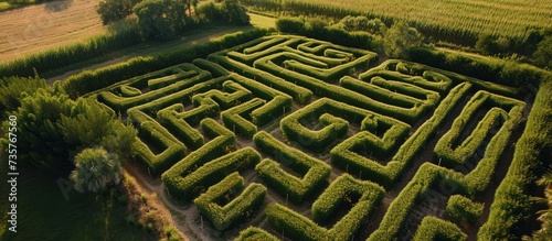 An artistic labyrinth made of grass and automotive tires, surrounded by trees, creating a mesmerizing pattern in the landscape from an aerial view.