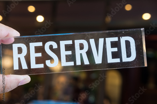 Reserved sign on hand with light bokeh background. Reserved sign for dinner