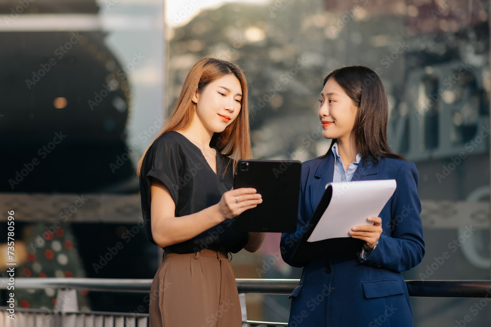 Businesswoman and woman going in city center in smart casual business style, talking, working together, stylish freelance people, holding coffee Businesswoman and woman going in city center in smart casual business style, talking, working together, stylish freelance people, holding coffee