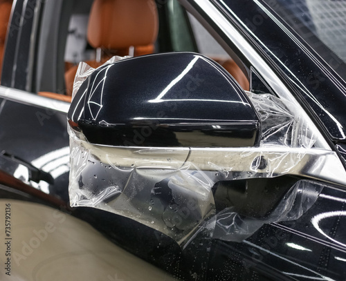 The process of installing PPF on the side mirror. PPF is a protective film for paint that protects the paint from scratches and gravel.Anti-gravity protection. PFF is installed. Car wrapping close-up.
