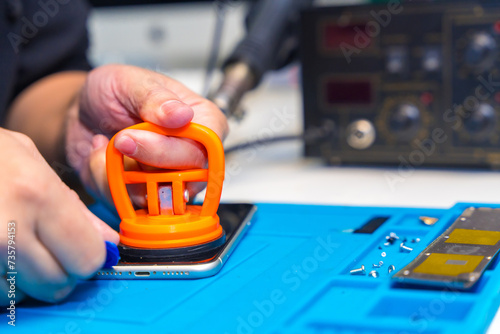 Man using pick and suction cup to repair a mobile