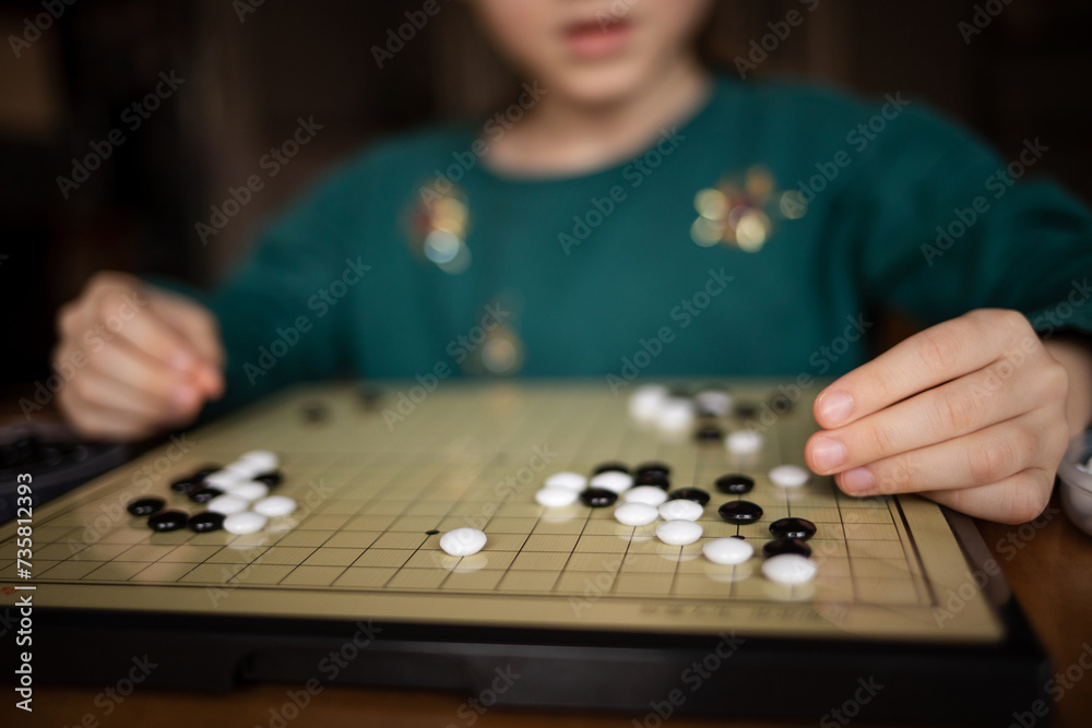 Fototapeta premium child playing game go. board logic strategy game for developing mind