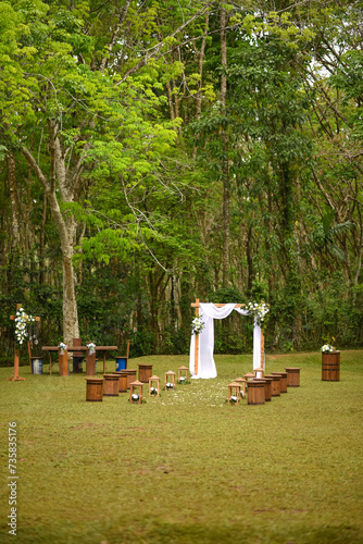 Portrait view of an outdoor wedding setup with wooden seats and floral decorations