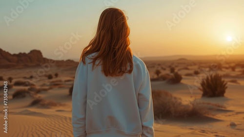 Redhead girl in white sweatshirt standing in the desert