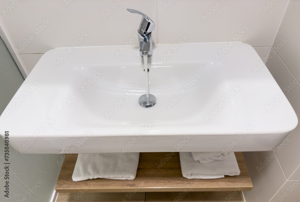 Fototapeta premium Water tap in washbasin. Bathroom faucet. Water Flowing From Faucet in Bathroom. Sink Water flowing from faucet. Saving water in sink. Wash Basin