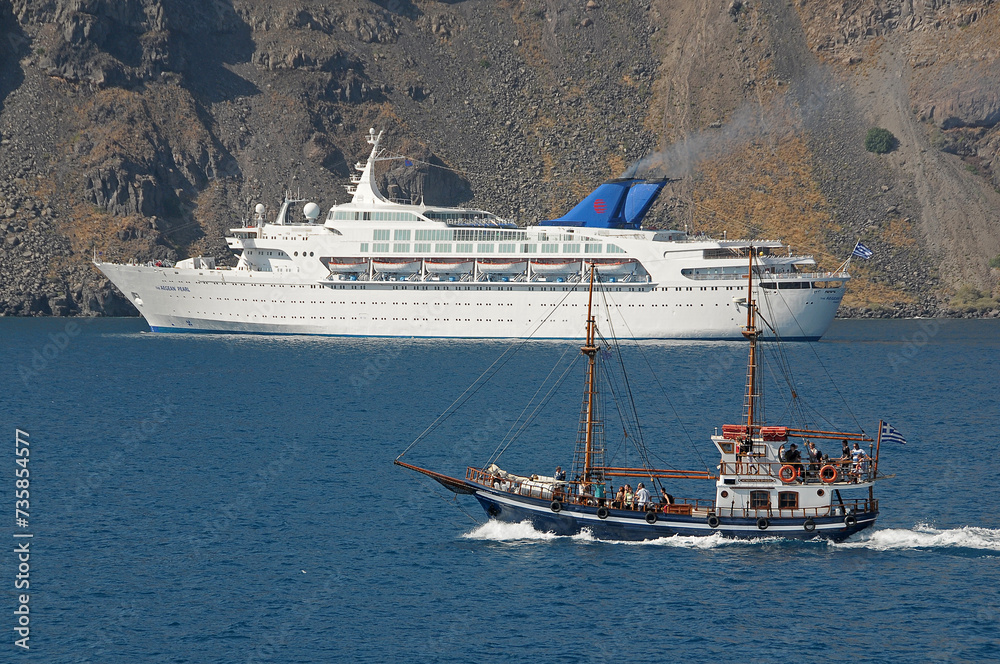 Velero y barco de crucero frente a la isla de Santorini en Grecia