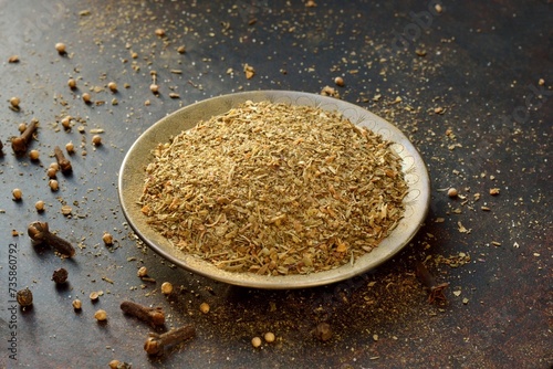 Garam masala - Indian dry seasoning, powder from a mixture of various spicy plants in a metal bowl on a dark background close-up. photo