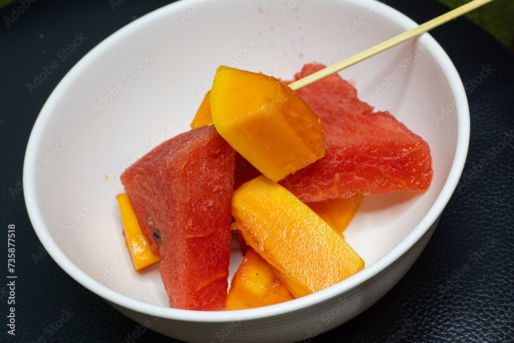 A high quality photo of fruit salad mixture of papaya and watermelon sliced and ready to eat with a stick A high quality photo of fruit salad mixture of papaya and watermelon sliced and ready to eat with a stick