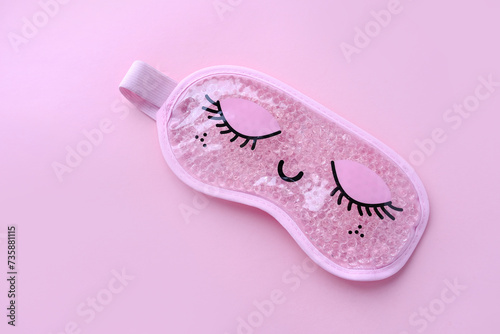 Pink sleep mask with closed eyes on it on pink background. Top view, flat layer. The concept of vivid healthy dreams.