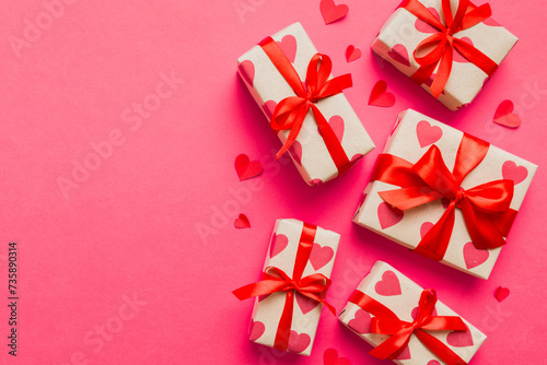 Top view photo of valentine day decorations gift box with red ribbon bow on colored background. Holiday gift boxes with top view