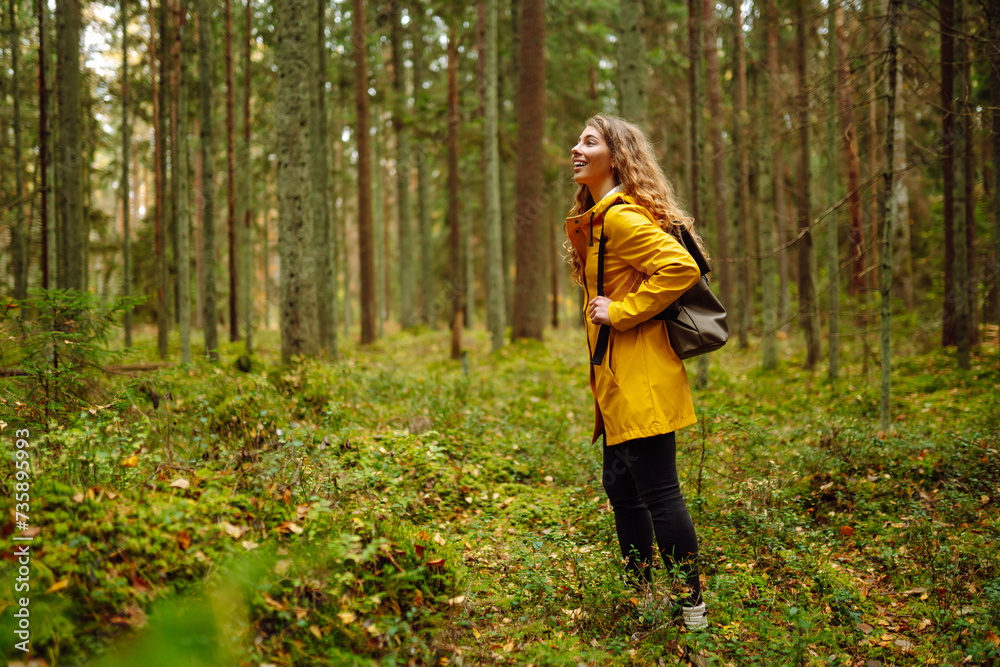 Pretty woman carrying a backpack in the forest in the autumn season. Traveler enjoying nature. Concept of trekking, active lifestyle. Adventures. Pretty woman carrying a backpack in the forest in the autumn season. Traveler enjoying nature. Concept of trekking, active lifestyle. Adventures.
