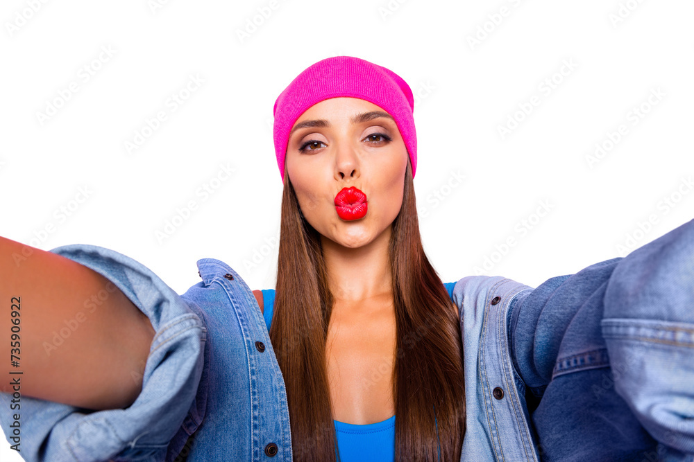 Charming blogger girl in a pink hat and blue body make selfie and sends air kiss isolated on vivid pink background