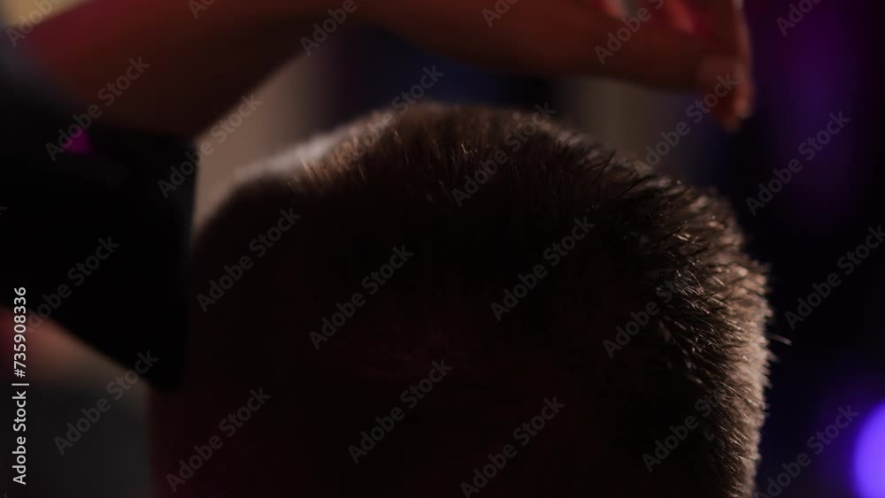 Close-up. A woman hairdresser blow-dries wet hair on a man's head while standing in a modern hairdressing salon Close-up. A woman hairdresser blow-dries wet hair on a man's head while standing in a modern hairdressing salon