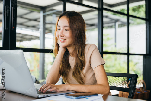 Happy businesswoman smiling sitting alone at cafe desk with laptop computer she looking out of window, portrait of beautiful woman smile in coffee shop in morning, freelance lifestyle