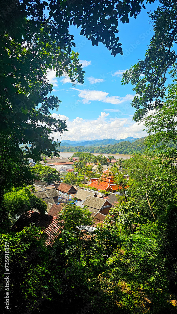 A breathtaking view from above of the historical town of Luang Prabang, nestled among lush greenery with the river meandering in the background
