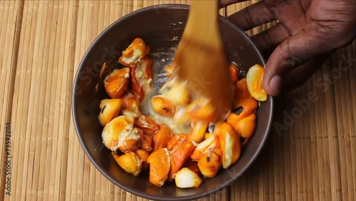 Crushing wild fruits of Trichilia emetica, also known as Natal mahogany or mafura, to make a creamy and delicious dessert photo