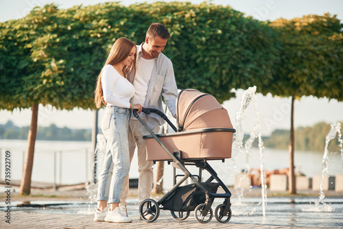 A young couple with a baby pram is walking together