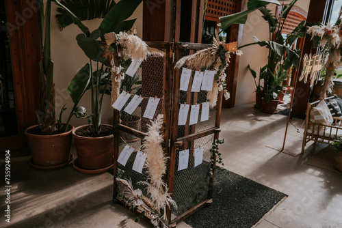 Estructura de madera con malla metálica con papeles para colgar, rincón decorativo, para anunciar dónde se sentarán los invitados a una boda. photo